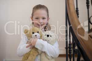 Young girl standing with soft toys at home