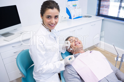 Portrait of dentist holding equipment while standing by patient