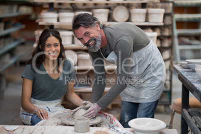 Portrait of male potter assisting female potter