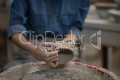 Mid section of female potter molding a cup