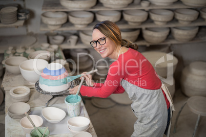 Portrait of female potter painting bowl