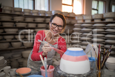 Portrait of female potter painting bowl