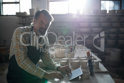 Portrait of male potter using digital tablet