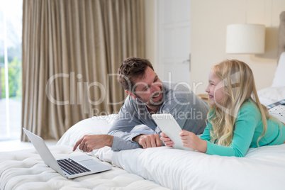 Father and daughter using laptop and digital tablet