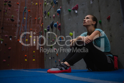 Thoughtful athlete looking up while relaxing in club