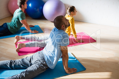 High angle view of yoga instructor with students practicing cobra pose in club