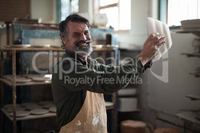 Portrait of male potter checking ceramic bowl