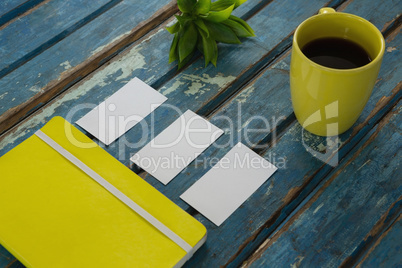 Blank visiting cards, diary, flora and black coffee on wooden plank