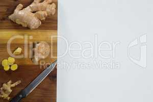 Directly above view of fresh chopped ginger with knife on wooden cutting board