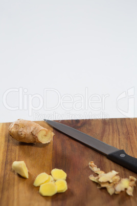 Close up of fresh ginger and knife on wooden cutting board