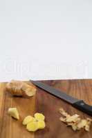 Close up of fresh ginger and knife on wooden cutting board