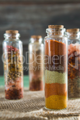 Various spices in bottles on wooden table