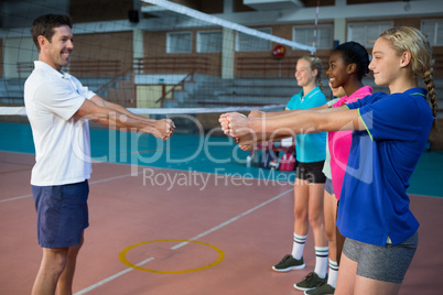 Male coach and female players performing stretching exercise