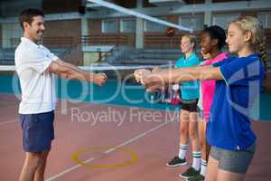 Male coach and female players performing stretching exercise