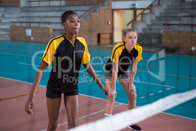 Female players playing volleyball in the court