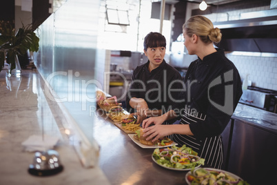 young female chefs talking while preparing food at kitchen counter