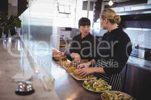 young female chefs talking while preparing food at kitchen counter