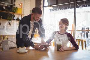 Young man showing digital tablet to woman