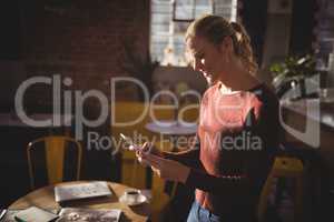 Smiling young blond woman using smartphone at coffee shop