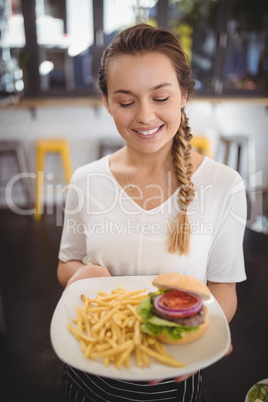 Smiling young waitress holding fresh junk food plate