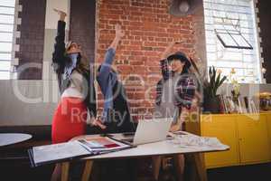 Excited young creative team standing with arms raised