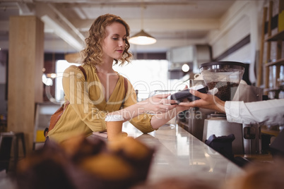 Young female customer paying through card at counter