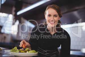 Portrait of smiling beautiful young waitress preparing salad at counter