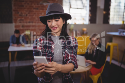 Smiling young attractive woman using mobile phone at coffee shop
