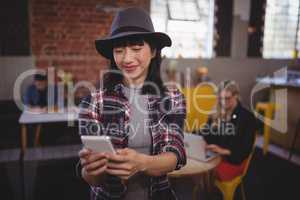 Smiling young attractive woman using mobile phone at coffee shop
