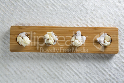 Overhead view of cauliflowers with cheese on cutting board