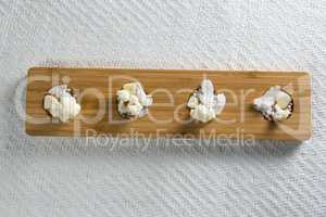 Overhead view of cauliflowers with cheese on cutting board