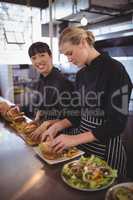 Portrait of smiling female chef preparing food with colleague at kitchen counter