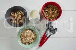 Bowls of various breakfast with milk jug and spoons