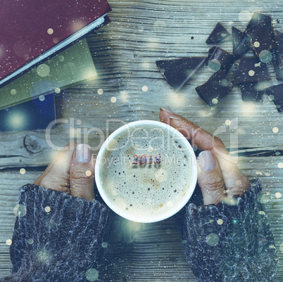 New Year Christmas. A cup of coffee or a cup of tea in his hand, and women crushed dark chocolate, stack of books. Falling gold snowflakes