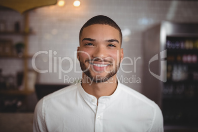 Portrait of smiling young man standing at coffee shop