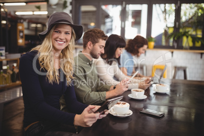 Smiling young woman sitting with friends at table in cafe