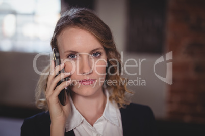 Portrait of confident young beautiful female editor talking on cellphone