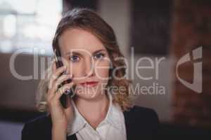 Portrait of confident young beautiful female editor talking on cellphone