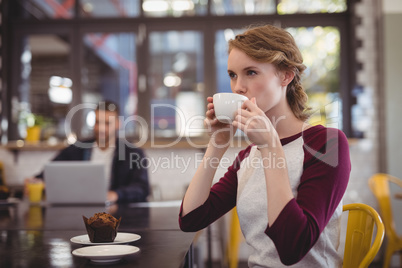 Beautiful young woman drinking coffee from cup at cafe