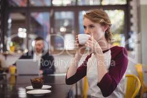 Beautiful young woman drinking coffee from cup at cafe