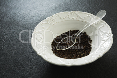 Black pepper in spoon and bowl