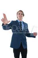 Young businessman holding glass interface while touching imaginary screen