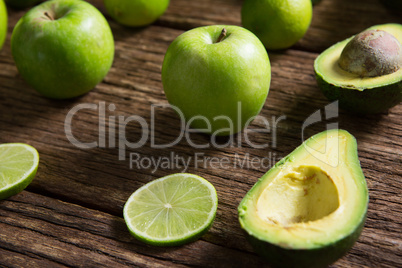 Lemon slice, avocado and green apple arranged on wooden table