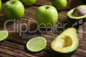 Lemon slice, avocado and green apple arranged on wooden table