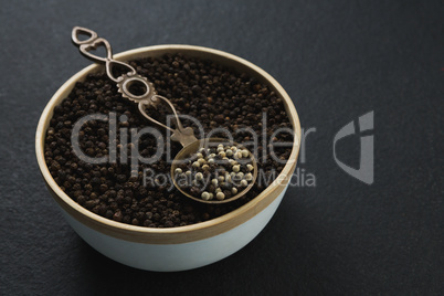 Black pepper and white pepper seeds in a bowl