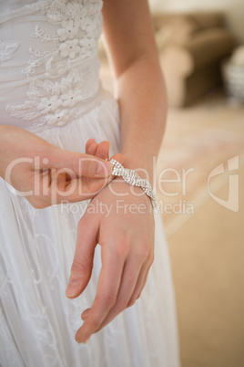 Midsection of bride wearing bracelet while standing at home