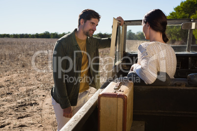 Man looking at woman sitting in off road vehicle