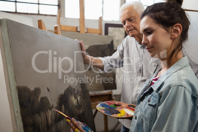 Senior man watching while artist painting on canvas