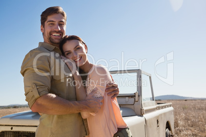 Portrait of happy young couple by off road vehicle