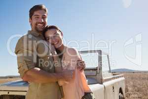 Portrait of happy young couple by off road vehicle